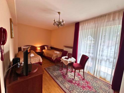 a living room with a room with a bed and a television at Pensjonat Szach in Krynica Zdrój
