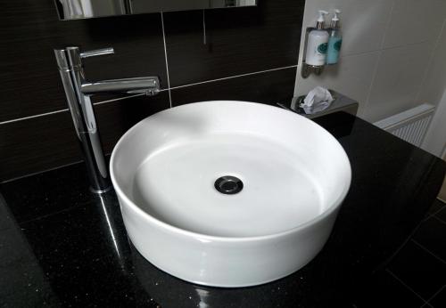 a bathroom with a white sink on a black counter at Kenmare Bay Hotel Lodges in Kenmare