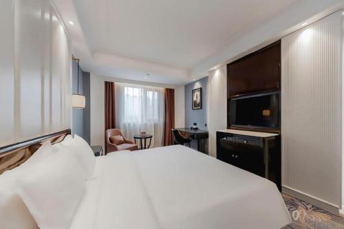 a hotel room with a white bed and a flat screen tv at Jinjiang Metropolo Hotel Nanjing Confucius Temple Branch in Nanjing