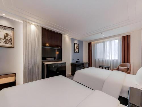 a hotel room with two beds and a desk at Jinjiang Metropolo Hotel Nanjing Confucius Temple Branch in Nanjing