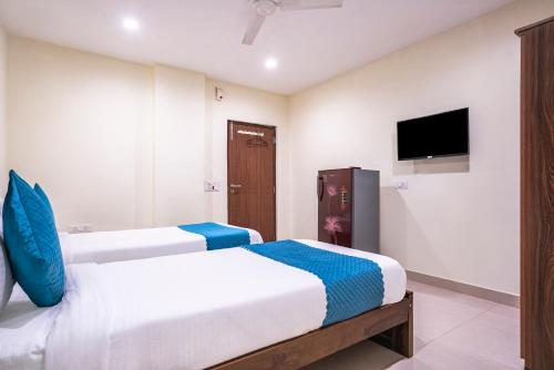 two beds in a hotel room with a tv at Blue Springs-Madhapur in Hyderabad