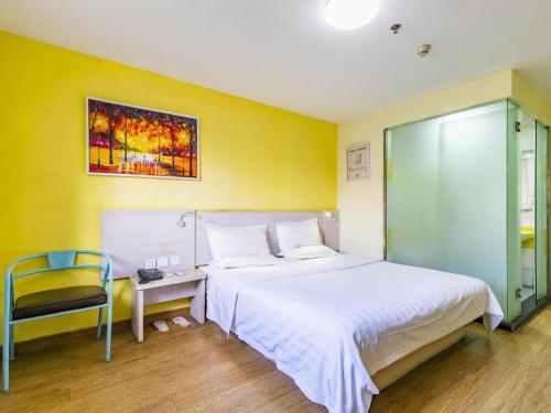 a bedroom with a large white bed and a chair at 7 Days Inn Tianjin Development Zone 3rd Street Wanli in Binhai