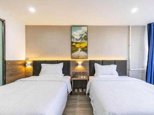 two beds in a hotel room with white sheets at 7 Days Inn Tianjin Development Zone 3rd Street Wanli in Binhai