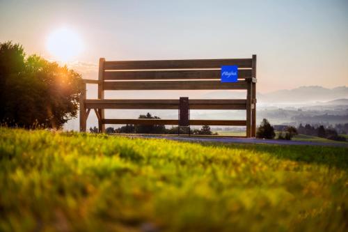 a bench sitting on the side of a hill with the sunset at Mittelburg Wellnesshotel in Oy-Mittelberg