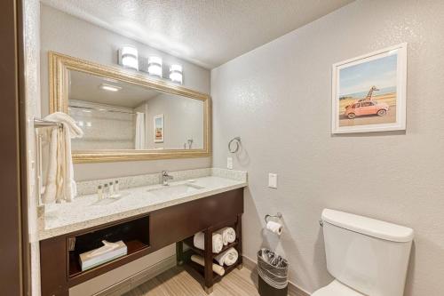 a bathroom with a sink and a toilet and a mirror at Amanzi Hotel, an Ascend Collection Hotel in Ventura