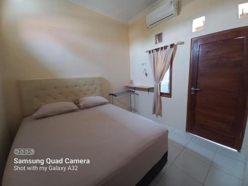 a bedroom with a bed and a wooden door at Niti Guest House in Tegalan
