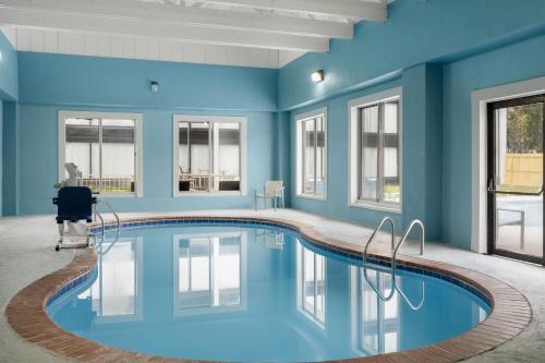 a pool in a room with blue walls and windows at Baymont by Wyndham Williamsburg I-64 in Williamsburg