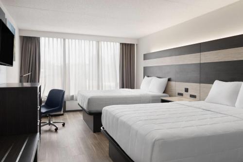 a hotel room with two beds and a television at Baymont by Wyndham Williamsburg I-64 in Williamsburg