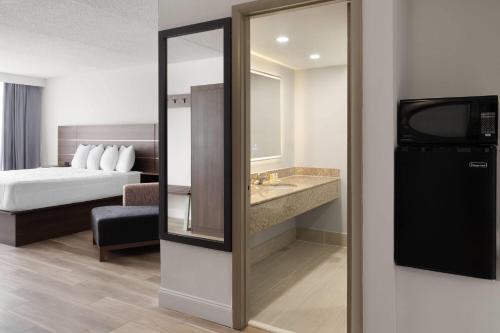 a hotel room with a bed and a mirror at Baymont by Wyndham Williamsburg I-64 in Williamsburg