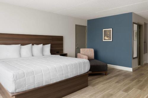 a hotel room with a bed and a chair at Baymont by Wyndham Williamsburg I-64 in Williamsburg