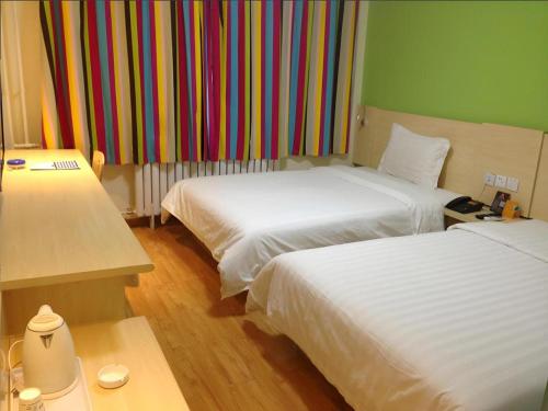 a hotel room with two beds and a colorful wall at 7 Days Inn Hohhot Hailiang Xinhua Square Metro Station in Hohhot