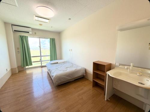 a bedroom with a bed and a sink and a tub at ハイ沖縄金武店トイレお風呂共用 プレオープン中駐車場有 ペット同伴可能長期滞在可能2025年10月より車貸し出しサービス有希望であればお申し付けください in Kin