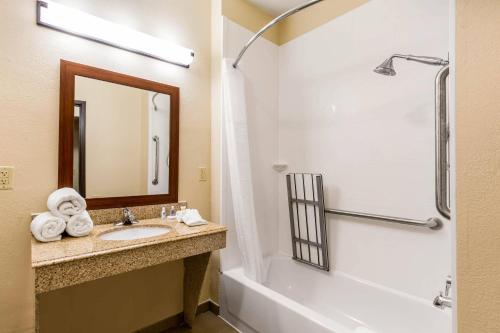 a bathroom with a sink and a tub and a mirror at Comfort Suites in Humble