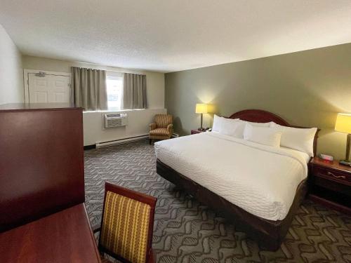 a hotel room with a large bed and a chair at Rodeway Inn in Sudbury