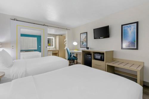 a hotel room with two beds and a tv at Hillstone Inn Tulare, an Ascend Collection Hotel in Tulare