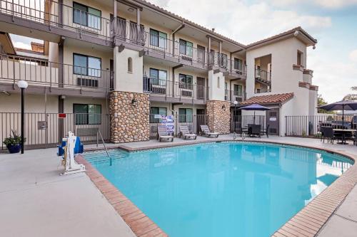 a pool in front of a hotel with tables and chairs at Hillstone Inn Tulare, an Ascend Collection Hotel in Tulare