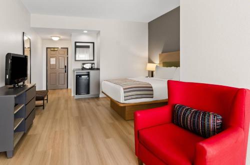 a hotel room with a red couch and a bed at Country Inn & Suites by Radisson, Roanoke, VA in Roanoke