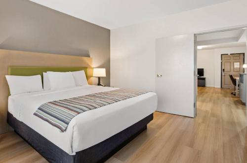 a bedroom with a large white bed and a hallway at Country Inn & Suites by Radisson, Roanoke, VA in Roanoke