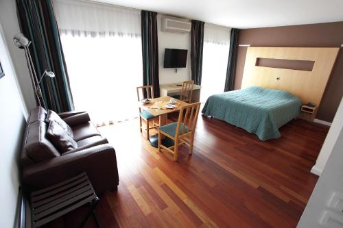 a room with a bed and a couch and a table at Hôtel la Scala in Pithiviers