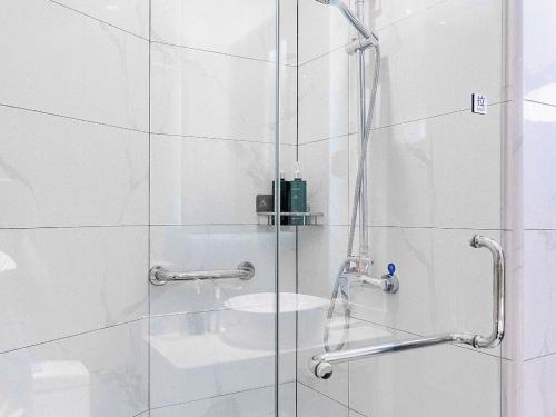 a shower with a glass door and a sink at Jinjiang Inn Zibo People's Park Liuquan Road in Zibo