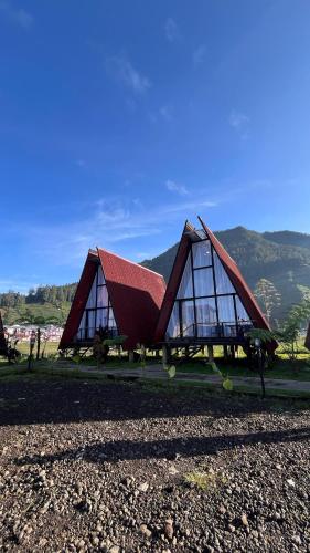 a building with a red roof with mountains in the background at Dieng Ceria Resort in Dieng