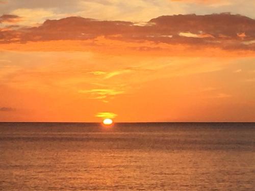 a sunset over the ocean with the sun in the sky at L'Escale du Mouillage in Saint-Pierre