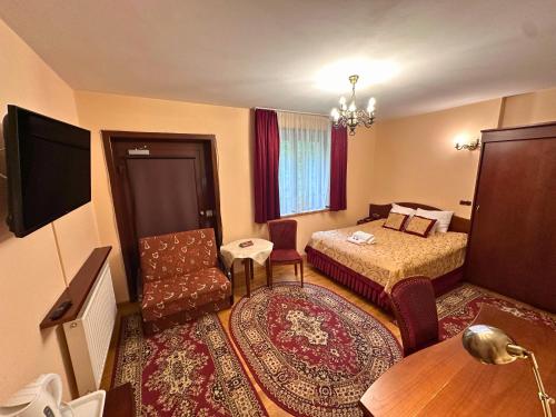 a hotel room with a bedroom with a bed and a chair at Pensjonat Szach in Krynica Zdrój