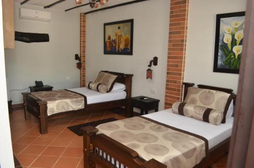 a room with two beds and a brick wall at Hotel El Virrey Boutique Honda in Honda