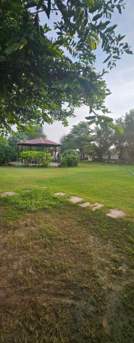 a green field with a gazebo in the background at Vashistfarmsadhranabamirpur in Gurgaon