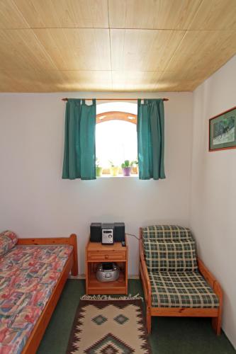 a room with two beds and a table and a window at Sörényes Udvarház in Pénzesgyőr