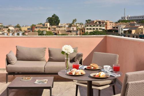a patio with a couch and a table with food on it at FH55 Grand Hotel Palatino in Rome