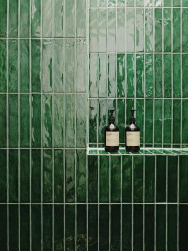 a green tiled bathroom with two bottles of soap at NOOK Stay am Checkpoint Charlie in Berlin