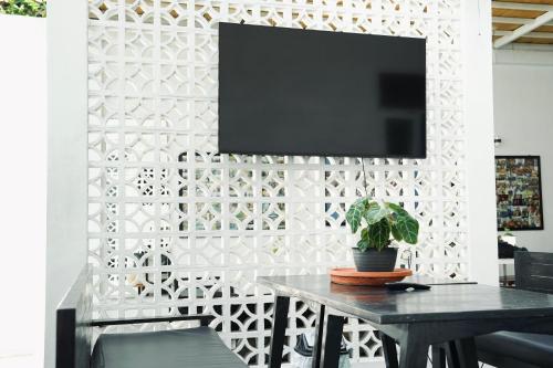a living room with a table and a tv on a wall at Dip & Doze Living in Canggu