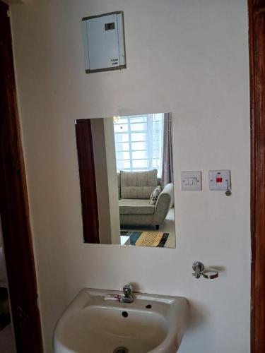 a bathroom mirror with a sink and a living room at Carlyle comfort home in Thika