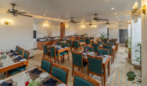 The Feel Munnar Resort في مونار: مطعم بطاولات خشبية وكراسي خضراء