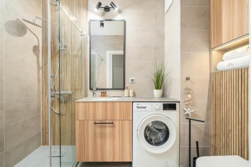 une salle de bains avec lave-linge et lavabo dans l'établissement Apartament Let's Sea z Basenem by BALTIC CLUB, à Gąski