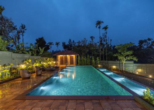 una piscina in un cortile posteriore di notte di The Feel Munnar Resort & Spa a Munnar