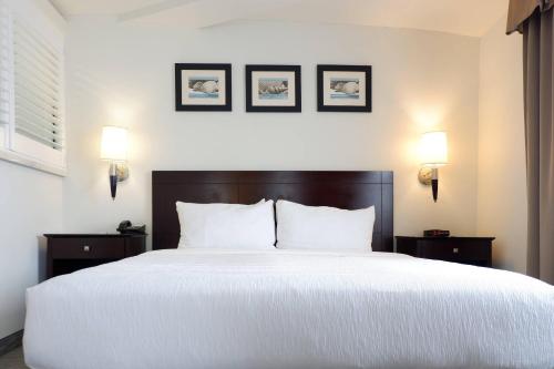 a bedroom with a large white bed with three pictures on the wall at The Volare, an Ascend Collection Hotel in San Clemente