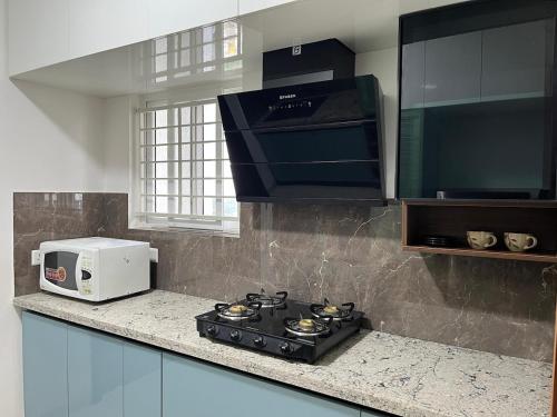 a kitchen with a stove and a microwave at 13th Floor 3BHK Flat with Mountain View in Bengaluru