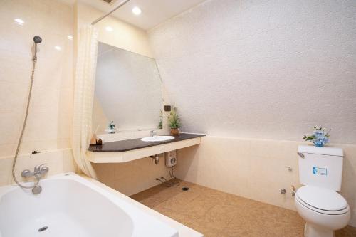 a bathroom with a tub and a toilet and a sink at 181 Ekkamai Studio Apartment in Bangkok