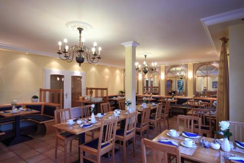 a restaurant with wooden tables and chairs and a chandelier at Hotel Zum Goldenen Stern in Prüm