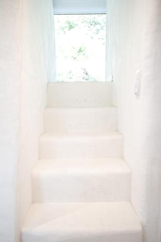 a white staircase in a white room with a window at Oia Moon in Blaimont