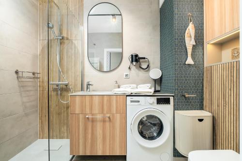 La salle de bains est pourvue d'un lave-linge et d'un miroir. dans l'établissement Apartament RIVIERA Let's Sea z Basenem by BALTIC CLUB, à Gąski