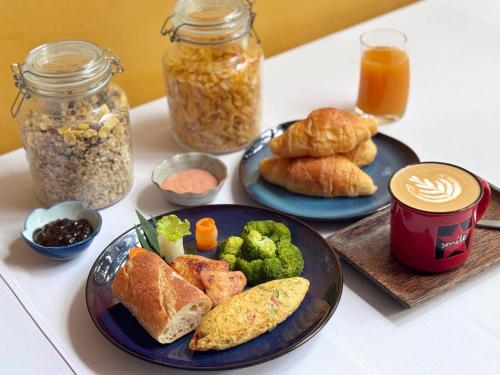a table with two plates of food and jars of breakfast foods at The Bliss Angkor in Siem Reap