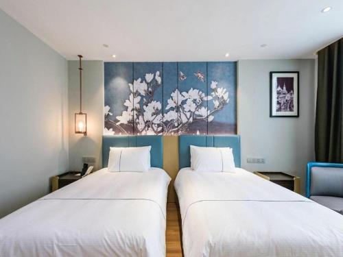 two beds sitting next to each other in a room at Magnotel Hotel Dongxing Guomen Port in Fangcheng
