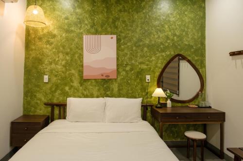 a bedroom with a bed and a mirror and a table at Benny Homestay Huế in Hue