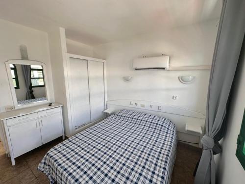 Un dormitorio pequeño con una cama y un espejo. en Dunaflor Gemelo 2, en San Bartolomé