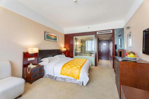 a bedroom with a large bed and a television at Shantou Golden Gulf Hotel in Shantou
