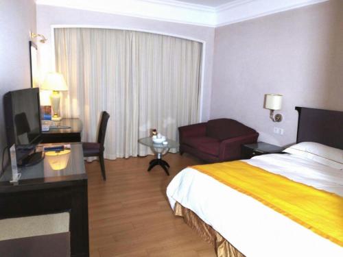 a hotel room with a bed and a desk and a room at Shantou Golden Gulf Hotel in Shantou