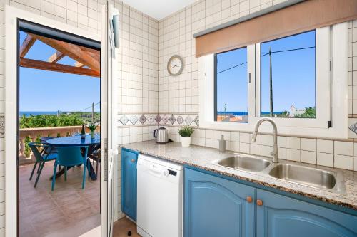 cocina con armarios azules y mesa con vistas en Villa Petre, en Cala'n Porter